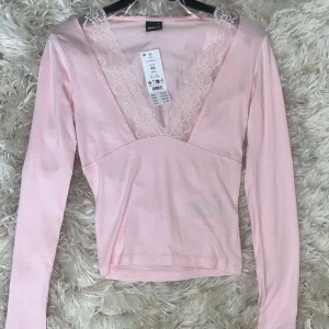 Spets topp - Säljer en söt rosa långärmad topp från Gina med v-ringning och spetsdetaljer. Perfekt för en stilren och feminin look. Toppen är i en mjuk och bekväm bomullsmix. Aldrig använd 💕💕