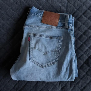 Levis 501 jeans i ljusblå denim - Säljer ett par klassiska Levis 501 jeans i ljusblå denim. De har en rak passform och är tillverkade i slitstarkt jeanstyg. Perfekta för en avslappnad stil. Jeansens ikoniska läderpatch och röda etikett på bakfickan ger en tidlös look.