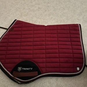 Trinity Shabrak  - Ett rött Shabrak från Trinity. Det är i bra skick förutom att det är slitet ner vid schabraket. (Se bilder). Pris kan diskuteras. STORLEK=FULL, Hoppschabrak.