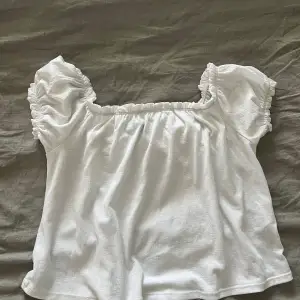 Säljer en söt vit topp från Gina Tricot med puffiga korta ärmar och elastisk halsringning.