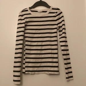 Randig långärmad tröja - Säljer en stilren randig tröja i svart och vit. 🖤🤍 Tröjan är långärmad och tillverkad av bomull med en liten del elastan för extra komfort. Perfekt för en avslappnad look. Har använt den ett fåtal gånger så är i väldigt bra skick🤗