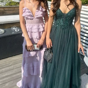 Ljuslila långklänning med volanger - så fin balklänning😍Det är en elegant ljuslila långklänning med volanger och spetsdetaljer! Bara använd en gång❤️ (första bilden är lånad, andra är min) Passar XS/S/M. Pris kan diskuteras men har ett min 