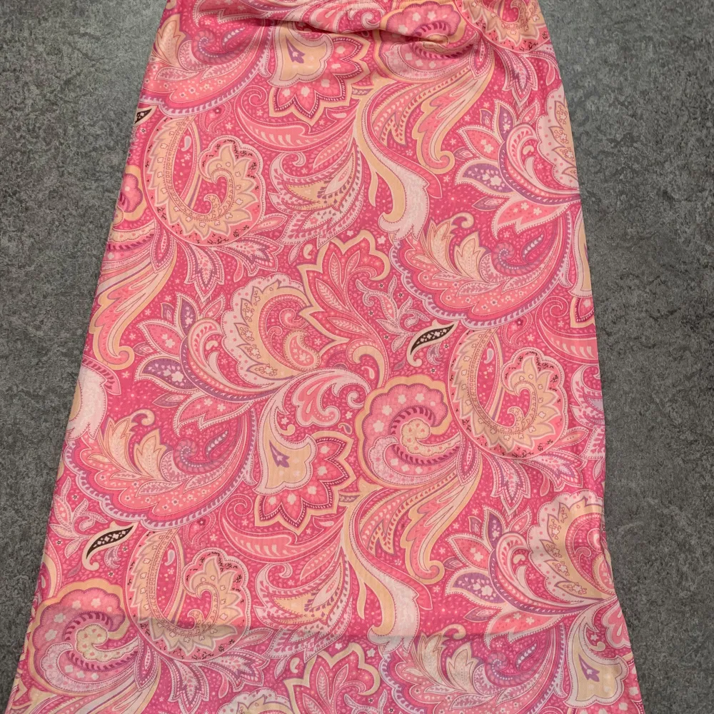 Säljer en snygg rosa klänning från Shein med ett livligt paisleymönster i ljusa toner. Klänningen är tillverkad i polyester och elastan, vilket ger en bekväm passform. Perfekt för sommarens varma dagar!. Hameet.