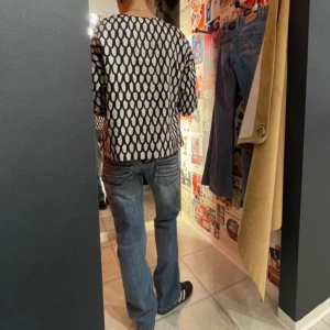 Blå jeansbyxor med bootcut och dragkedja på fickorna - Snygga blå jeans med bootcut-stil och låg midja. Byxorna har flera fickor och en dragkedja backtill Perfekta för en cool look där jeansen gör de lilla extra. Midjemått: 36cm tvärs över. Benlängd: 97cm
