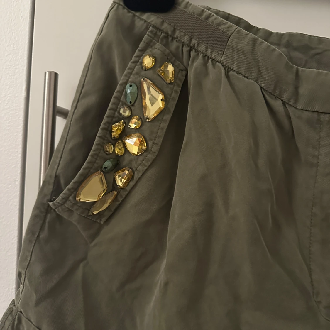 Olivgröna shorts med dekorativa stenar - 1