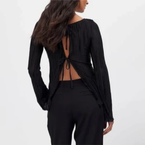 Svart långärmad topp med öppen rygg - Snygg svart topp med långa ärmar och en elegant öppen rygg med knytning. Perfekt för en stilren look. Från nakd i strl xs , aldrig använd