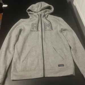 Grå zip hoodie från Race Marine - Grå hoodie från Race Marine med dragkedja och huva. Tillverkad i ett mjukt material som ger en bekväm passform.