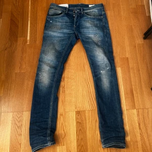 Blå jeans från Dondup - Snygga blå jeans från Dondup med en klassisk femficksdesign och knappgylf. Jeansen har storleken W30 och snygga slitningar. 