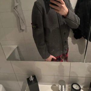 Grå kofta från Stone Island - Säljer en stilren grå kofta från Stone Island med knappar framtill och en ikonisk logga på ärmen. Perfekt för kyligare dagar med sin mjuka och bekväma passform. Ett måste för garderoben! 🧥Hittade samma tröja fast i beige på miinto och där står det nypris 13,500kr mitt pris 2700 (priset är inte hugget i sten😜)