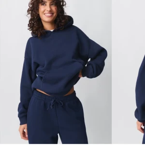 Mörkblå hoodie från Gina Tricot - Säljer en mörkblå hoodie från Gina Tricot, basically basics-kollektionen. Den har en klassisk design med en stor ficka framtill och en bekväm huva. Perfekt för en avslappnad stil. köpt för 359kr