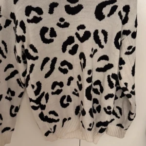 Vit och svart leopardmönstrad tröja från Boohoo - Säljer en snygg vit tröja med svart leopardmönster från Boohoo.  Den är långärmad med ribbade muddar vid ärmslut och nederkant. Använd få gånger