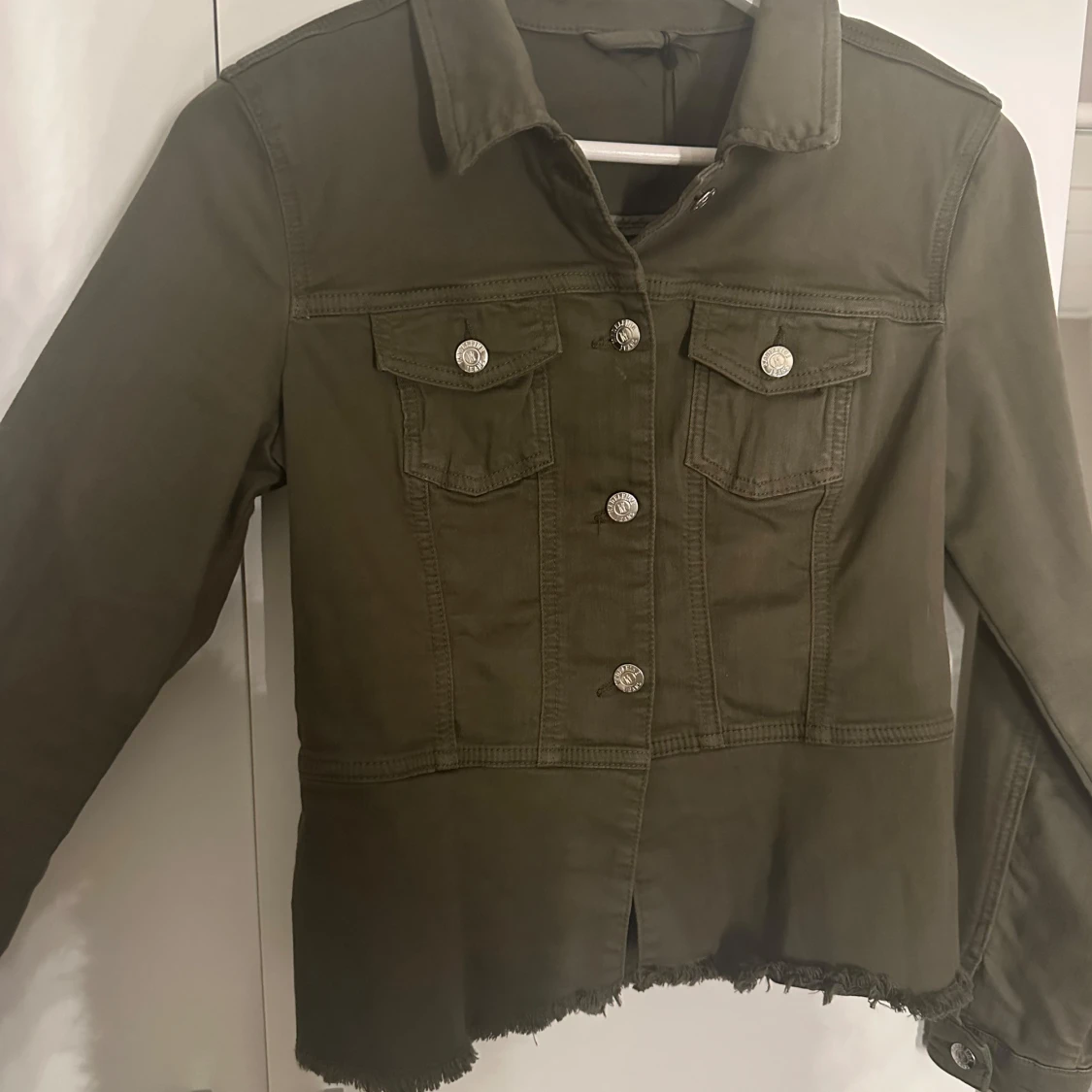 Olivgrön jacka med volangdetalj