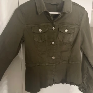 Olivgrön jacka med volangdetalj - Snygg olivgrön jacka med knappar och volangdetalj i nederkant. Superfin nu till vården och sommaren!💕🌸Hör av er för fler bilder eller frågor.