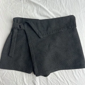 Kjol/shorts  - Svart Kjol med shorts under. Spänne i midjan och prickigt mönster. 