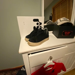 Svarta sneakers från Eytys - Snygga svarta sneakers från Eytys med en tjock beige sula och dragkedja baktill. Skorna har en stilren design med en lila detalj på baksidan. Perfekta för en trendig look.