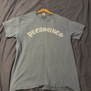Blå t-shirt från Pleasures - Säljer en väldigt snygg t-shirt från pleasures.  Perfekt till sommaren. Tröjan är köpt för 800kr