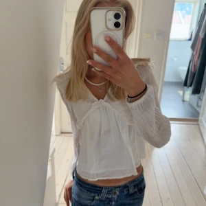 Vit blus med volangdetaljer - Supersöt vit blus med långärmade, lätt transparenta ärmar och volangdetaljer framtill💘 Blusen har v-ringning och är luftig. Jag har använt den i alla årstider så den passar verkligen till allt❣️ 