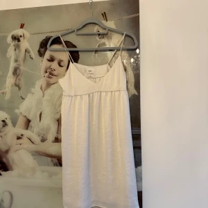 Vit sommarklänning från Wilfred - Säljer en söt vit klänning från Wilfred i storlek XS. Klänningen har tunna axelband, v-ringad hals och ett lätt, flowy fall. Perfekt för varma dagar och har en enkel, stilren look. Materialet känns mjukt och har en lätt glansig yta.