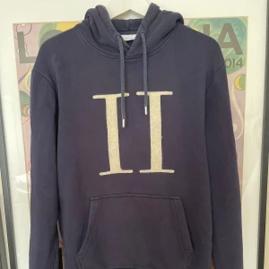 Mörkblå hoodie från Les Deux - Säljer en mörkblå hoodie från Les Deux med stor vit II-logga framtill. Tröjan har huva med snörning och en klassisk känguruficka. Kom privat för fler funderingar och frågor:) 