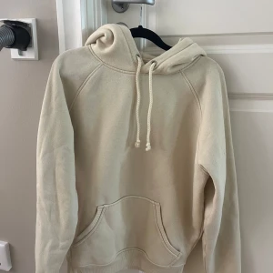 Beige hoodie från Bik Bok med huva - Säljer en beige/gul hoodie från Bik Bok i storlek XS. Tröjan har en stor huva med snörning och en klassisk magficka framtill. Materialet är mjukt och känns som bomull, perfekt för chill dagar. Långärmad och enkel att matcha med jeans eller leggings.