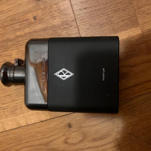 Ralph's Club Parfum svart flaska - Snygg parfym från Ralph Lauren, Ralph's Club Parfum, i en stilren svart matt flaska med silverdetaljer och logga framtill. Flaskan har en unik, nästan platt form och ett metalliskt lock. Perfekt för dig som gillar exklusiva dofter.