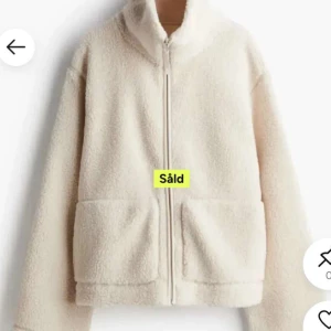 Beige teddyjacka med dragkedja - Mysig beige teddyjacka med hög krage och dragkedja framtill. Jackan har två stora fickor och är tillverkad i ett fluffigt material som håller värmen. Perfekt för kyliga dagar och enkel att matcha med olika outfits.