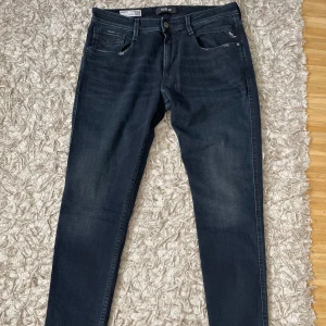 Replay Bronny mörkblå jeans slim fit - Snygga mörkblå jeans från Replay, modell Bronny, med slim fit och klassisk femficksdesign. Jeansen har diskreta slitningar på bakfickorna med en stilren look. Perfekt för dig som vill vara modern och stilren.