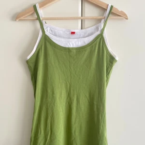 Grön och vit linnetopp från Esprit - Snygg tvåfärgad linnetopp från Esprit i grönt och vitt. Toppen har smala axelband och dubbla lager som ger en cool kontrast vid kanter och nederdel. Broderad Esprit-logga framtill. Perfekt till sommaren och enkel att styla med jeans eller kjol.