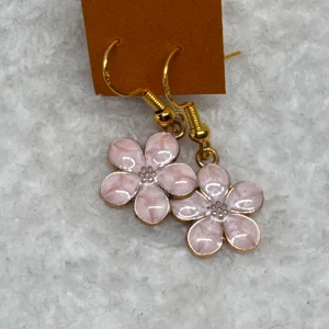 Rosa blommiga örhängen i guldton - Supersöta örhängen med hängande blommor i ljusrosa och guldfärgade detaljer. Blommorna har fem kronblad och små pärldetaljer i mitten. Perfekta för att ge en gullig touch till din look.