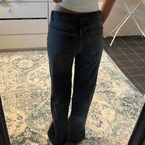Vida svarta jeans med hög midja - Säljer ett par svarta jeans med raka ben och hög midja. Jeansen har klassisk femficksdesign och bälteshällor. Snygg tvättad svart färg som passar till allt. Perfekta för dig som gillar en avslappnad men ändå stilren look.