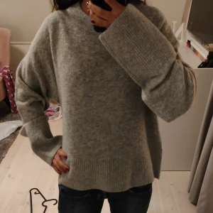 Grå stickad tröja från Gina Tricot - Mysig grå stickad tröja från Gina Tricot med breda ribbade muddar och avslappnad passform. Perfekt för lager-på-lager och chill dagar. Enkel att matcha med jeans eller kjol för en clean look. Helt ny med prislappen kvar! Sitter som en 34/36 men är i barn storlek.💞