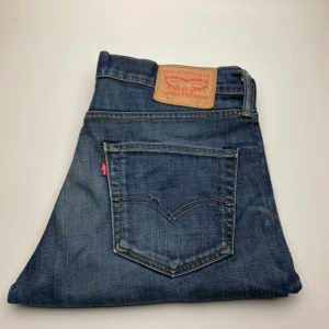 Levi's 511 blå jeans - Säljer ett par klassiska Levi's 511 jeans i blå denim. Modellen är slim fit med raka ben och snygga detaljer som den ikoniska läderpatchen bak och röda Levi's-taggen på bakfickan. Perfekta till sneakers eller boots.