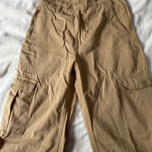 Beiga cargopants från Pull&Bear - Säljer ett par snygga beiga cargopants från Pull&Bear med stora fickor på sidorna 