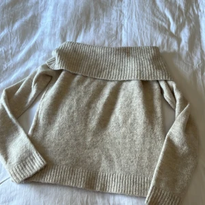 Beige offshoulder stickad tröja Gina Tricot - Supermysig beige stickad tröja från Gina Tricot med bred ribbad offshoulder-krage och långa ärmar.Tröjan har ribbade muddar och är i en mjuk, varm kvalitet. Den ser mörkare ut på bilderna men är som på hemsidan igentligen. Använd 1 gång. Säljer för den inte kommer till användning.