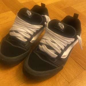 Van knu skool - Säljer ett par klassiska Vans sneakers i svart och vitt med vit sula och tydliga kontrastsömmar. Skorna har den ikoniska vågformen på sidan, tjocka vita snören och en slitstark gummisula med rutmönster. Perfekta för dig som gillar streetstyle och skate.