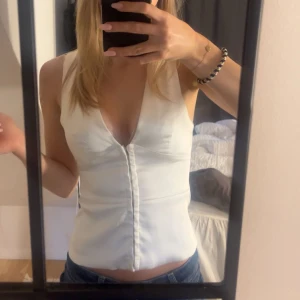 Vit satin topp, Zara - Snygg vit satin topp/väst ifrån Zara med djup v-ringning och figur passform. Väldigt stilren och snygg, passar till allt från fest till vardag! 💗