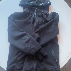 Svart hoodie med goggles från C.P. Company - Svart hoodie från C.P. Company med goggles. Skick 10/10. Köpt för 4K i London i CP companys egna butik. Priset är ej hugget i sten🫡