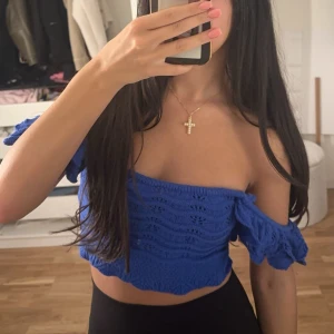 Blå croppad stickad topp H&M XS - Superfin blå croppad topp från H&M i stickat material. Toppen har volangdetaljer på axelbanden och kan bäras både offshoulder och med axelbanden uppe. Perfekt för sommarens alla tillfällen!