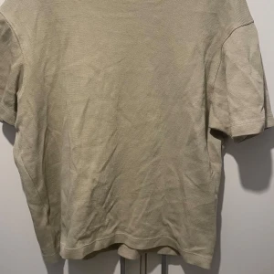 Grön/beige ribbad t-shirt från Zara i bomull - En ribbad Grön/beige ribbad t-shirt från Zara i storlek S. T-shirten har korta ärmar, rund hals och är tillverkad i ett mjukt bomullstyg. Perfekt för en clean och avslappnad stil.