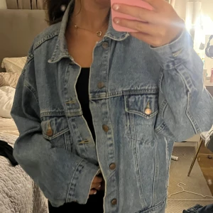 Oversized jeansjacka från Structure - Säljer en oversized ljusblå jeansjacka från Structure. Jackan har klassisk design med stora bröstfickor, metallknappar och bred krage. Perfekt för dig som gillar en avslappnad och trendig look. Materialet är 100% denim och jackan har långa ärmar.