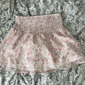 Blommig volangkjol från Gina Tricot - Supersöt kort kjol från Gina Tricot. (Young) Kjolen har bred smock i midjan och volangdetaljer🩷