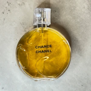 Chanel Chance parfym 100 ml - Chanel Chance parfym i en rund glasflaska med tydlig guldfärgad vätska och elegant transparent lock. Flaskan rymmer 100 ml och har klassisk svart text på framsidan. En ikonisk doft från Chanel som utstrålar lyx och stil. ‼️‼️‼️‼️. Det finns ingen kartong ‼️‼️‼️‼️