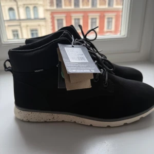 Svarta boots från McKinley strl 45 - Svarta boots från McKinley med grov, vit och svart sula och snörning framtill. Ovandelen är i syntetmaterial och skon har en sportig, modern look. Perfekta för höst och vinter med robust yttersula för bra grepp.