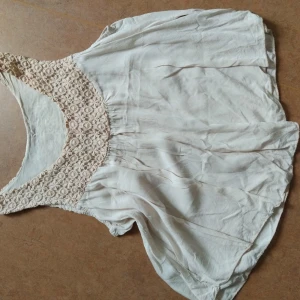 Ärmlös Blus/linne - En ljust rosa/beige ärmlös blus/topp som är lite flowy. Virkad överdel på fram och baksida. 100% viskos. Storlek XS, passar även S. Fint använt skick, inga fläckar eller hål.