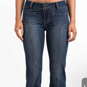Blå bootcut jeans med fickor - Snygga mörkblå bootcut jeans med markerade sömmar och stora fickor fram. Jeansen har dubbla knappar i midjan och coola bakfickor med lock och knapp. Inga defekter används 1-3 gånger. (Storlek S regular)