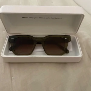 Olivgröna solglasögon från Chimi - Snygga solglasögon från Chimi i olivgrönt transparent acetat med fyrkantig form och bruna tonade glas. Diskreta silvriga detaljer vid gångjärnen och logga på skalmen. Kommer med vit hård förvaringsbox. Modell 04