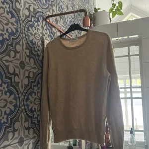 Stickad Kashmir/merinoulls tröja från Gran Sasso - Säljer en stilren beige stickad tröja från Gran Sasso. Tröjan har rund halsringning, långa ärmar och ribbade muddar. Perfekt för lager-på-lager och enkel att matcha med olika outfits. Klassisk och tidlös design.