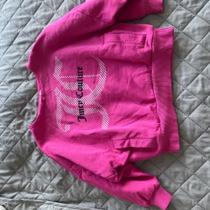 Rosa Juicy Couture sweatshirt - Superfin rosa sweatshirt från Juicy Couture med stort tryck framtill i vitt och svart. Tröjan har ribbade muddar vid ärmslut och midja samt en klassisk crewneck. Perfekt för dig som gillar färg och vill sticka ut lite extra.