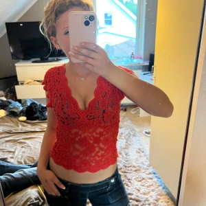 Röd spetsblus från Zara - Säljer en röd, croppad spetsblus från Zara med v-ringning och korta ärmar. Perfekt för dig som vill sticka ut med en färgstark och feminin look.