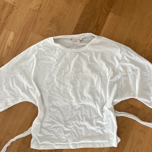 Vit omlottopp med knyt från Nelly - Säljer en vit omlottopp från Nelly i storlek L. Men skulle säga att den är mer åt M. Toppen har korta ärmar, rund halsringning och knytband i midjan som ger en snygg och avslappnad look. Perfekt till jeans eller kjol för en enkel men trendig stil.❤️